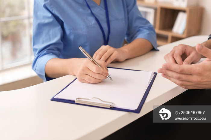 Young female receptionist working with patient in clinic, closeup