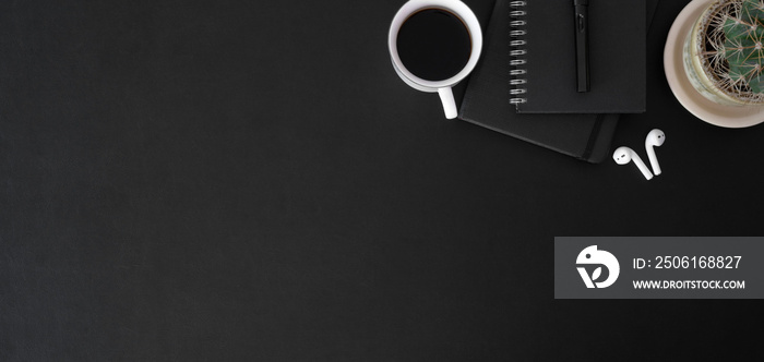 Top view of dark trendy workplace with coffee cup and office supplies on black table