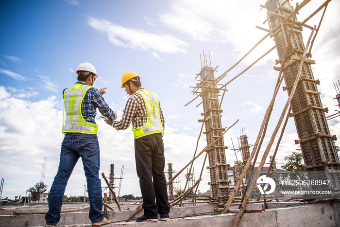 Male engineer talking with worker at a construction site with a tablet computer