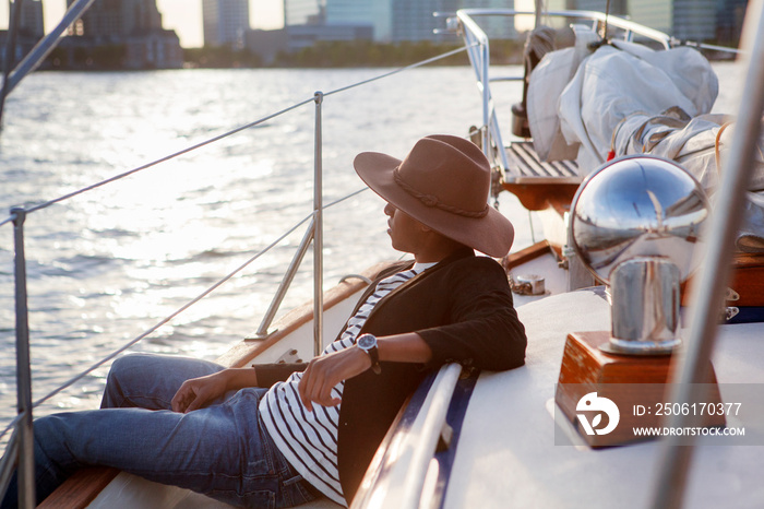 Young man looking at city while travelling by sailboat