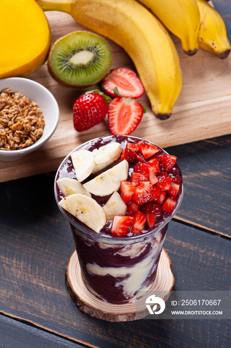 .Brazilian frozen açaí in a plastic cup with condensed milk and tropical fruits. Fruit from the Amaz