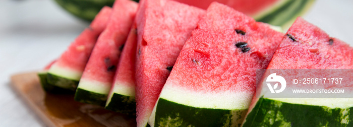 Sliced watermelon on bamboo board over white wooden surface, side view. Close-up.