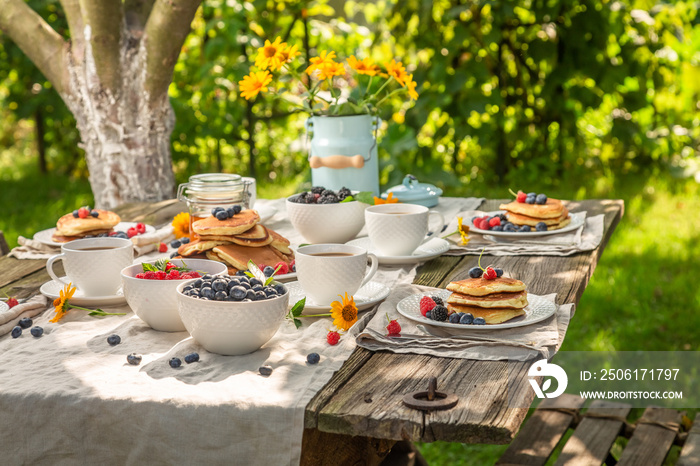 Delicious pancakes with raspberries and blueberries in summer garden