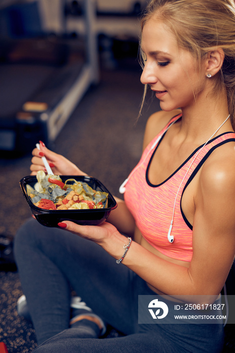 女性坐在健身房吃健康食物的侧视图。健康的生活方式概念。