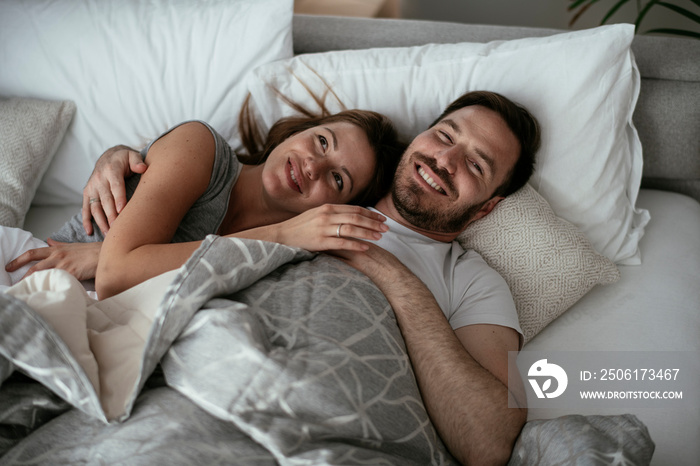 Young loving couple in bed. Happy couple relaxing in bed.