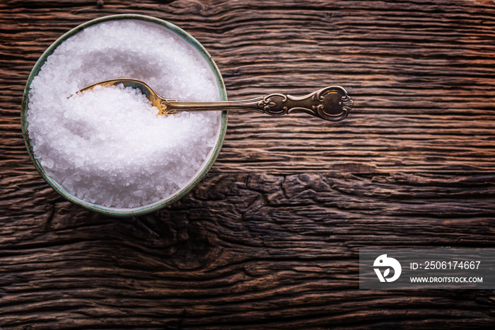 Salt. Sea salt retro fork in bowl on rustic oak table.