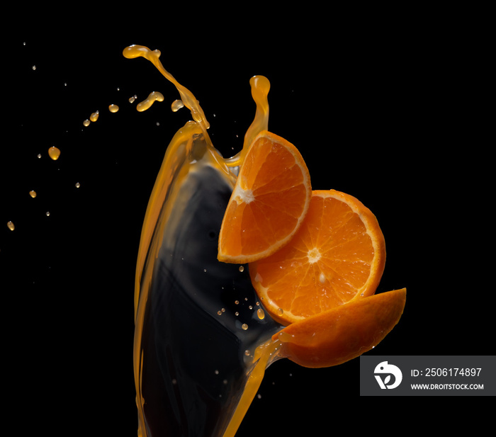 Orange juice with orange fruit slices splash or explosion flying in the air isolated on black backgr