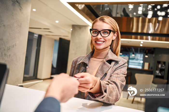 Young woman in hotel check in at reception or front office being given key card