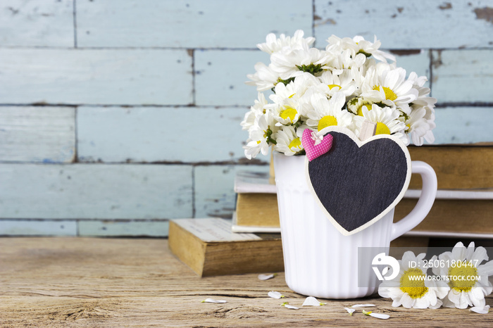 Daisy flowers in white cup with blank wood heart