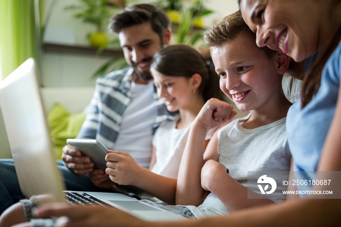 Happy family using laptop and digital tablet in the living room