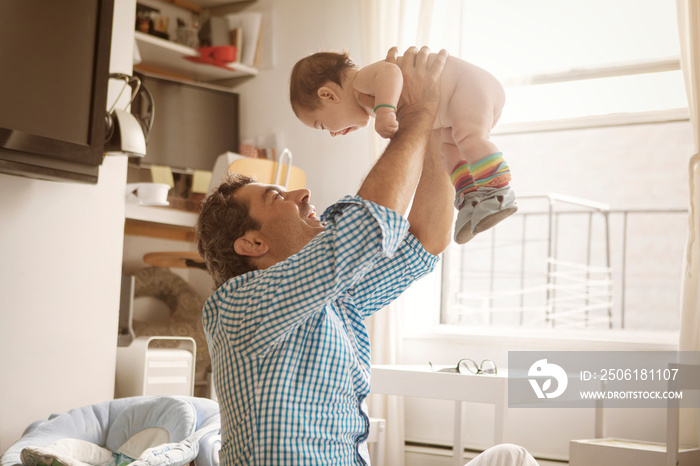 Smiling father playing with his daughter at home