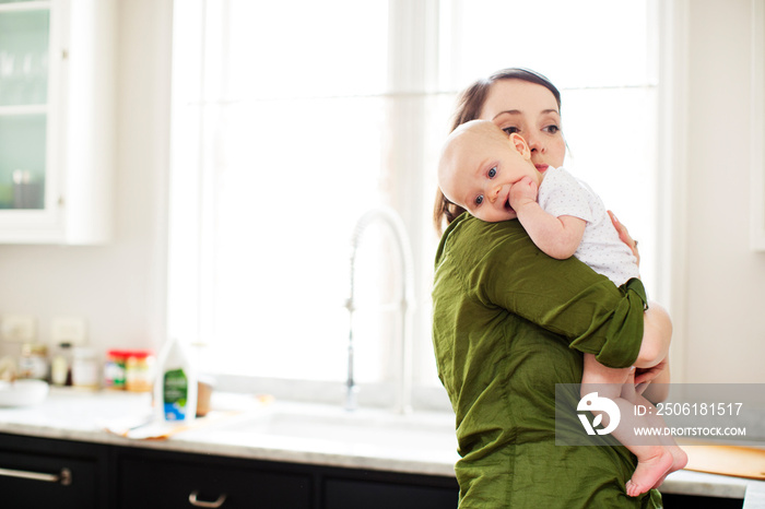 Mother holding her baby son (2-5 months) in kitchen