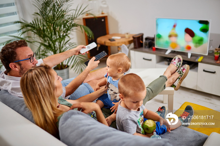 Young parents watching TV with baby boys.