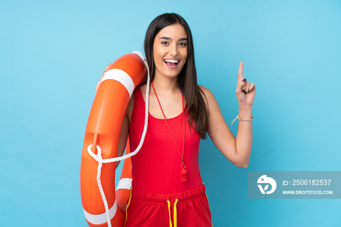 Lifeguard woman over isolated blue background with lifeguard equipment and pointing up a great idea