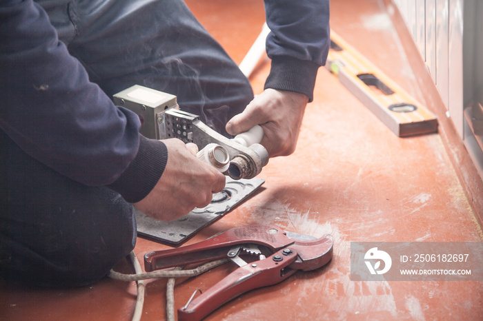 Worker connecting plastic pipe. Installing water heating radiator