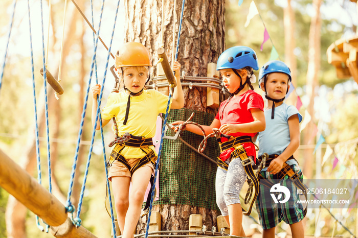 Child in forest adventure park. Kids climb on high rope trail. climbing outdoor amusement center for