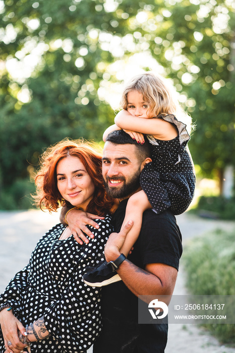 Happy parents with a small daughter sitting on the shoulders