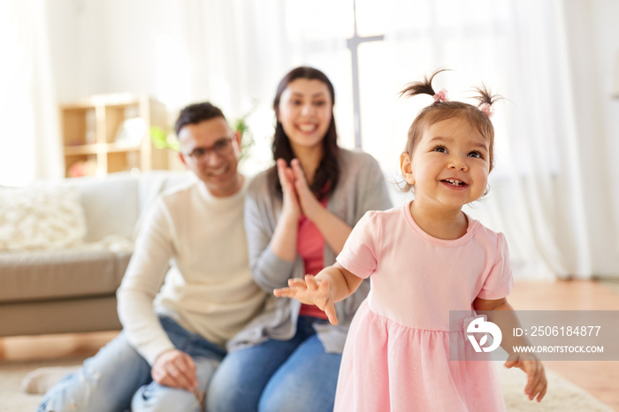 family and people concept - happy little daughter with mother and father at home