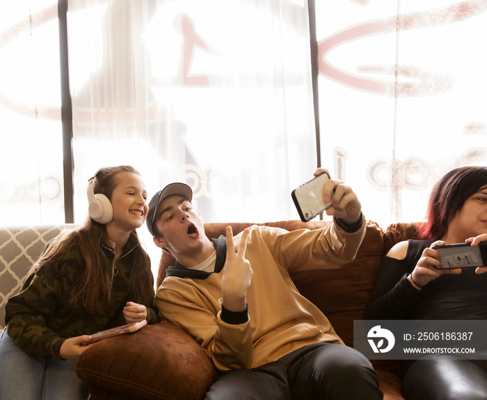 Young man taking selfie with cute girl while sitting on chairs against window in dance studio