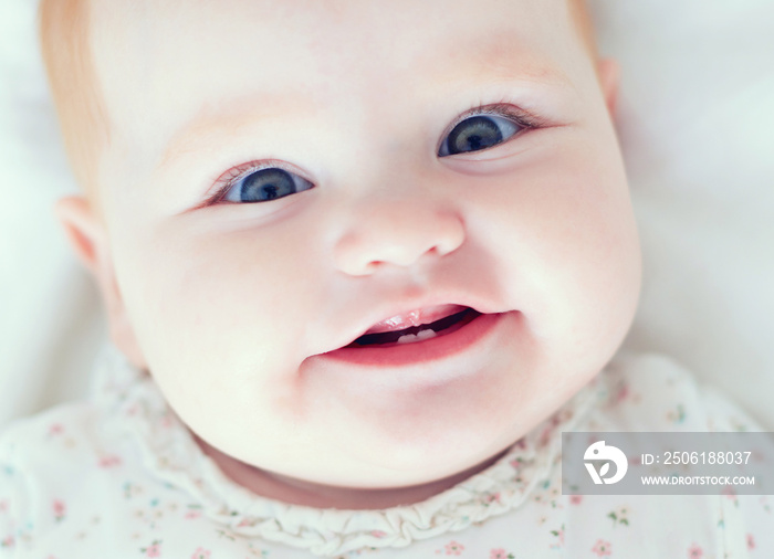 top view of infant baby girl, smilyng with her first two teeth