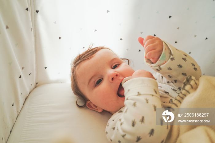 Portrait of a little playful baby in her cradle