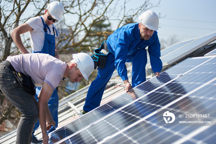 Male engineers installing stand-alone solar photovoltaic panel system. Electricians mounting blue so