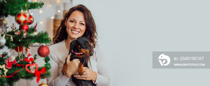 Portrait of a beautiful woman at home with her pet dog at Christmas time.