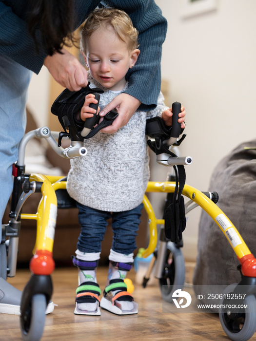 Mother assisting son with cerebral palsy in walking�