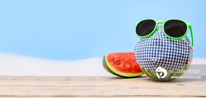 带着新鲜西瓜的创意简约夏季海滩度假。戴上太阳镜和口罩是因为