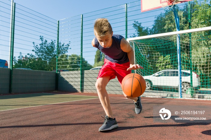 Boy teenager playing basketball in city basketball court