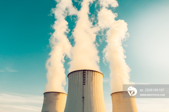 A Power plant with white smoke over its chimneys