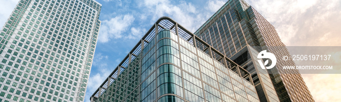 Modern city building architecture with glass fronts on a clear day in London, England at sunrise pan