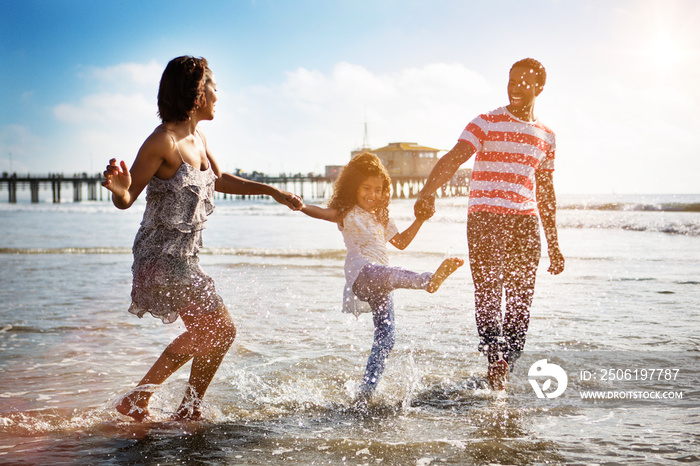 Parents with daughter (4-5) walking on beach