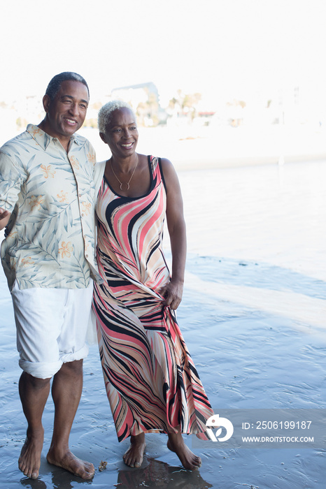 Happy senior couple on wet sand beach