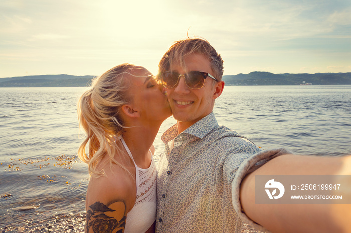 Smiling Young Man Taking Selfie With Girlfriend At Beach