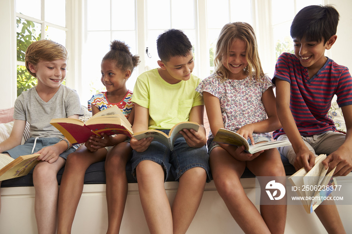 Group Of Multi-Cultural Children Reading On Window Seat