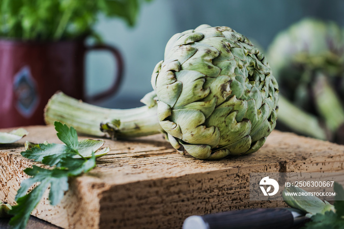 fresh ripe organic artichokes on dark rustic wooden background 