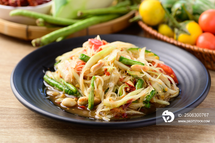 Thai food (Som tum), Spicy green papaya salad with vegetables on wooden table