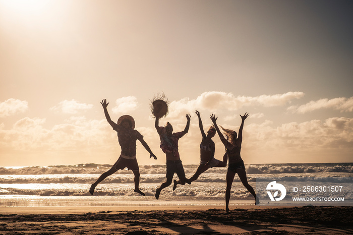 Group of people jump happy together at the beach during sunset with sky in background and silhouette