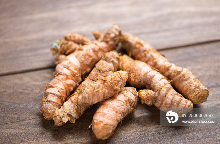 Close-up of turmeric root on brown wooden table. Spice for health and ingredient of Indian cuisine.