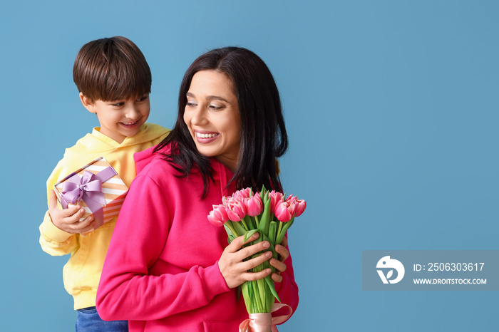 Little son greeting his mother on color background