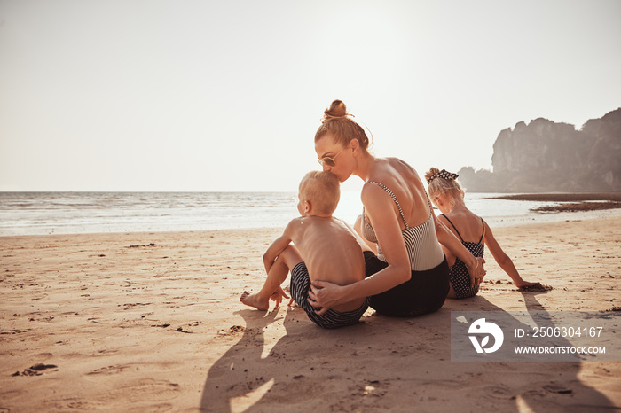 Loving Mother sitting with her children on a sandy beach