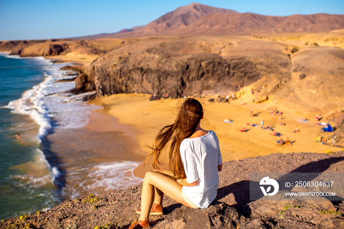 年轻的女游客坐在斯普兰萨罗特岛的帕帕加约海滩上欣赏美景