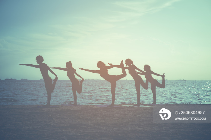 Yoga class outdoor on the sandy beach at sunset,Healthy Lifestyle concept,vintage filter effect