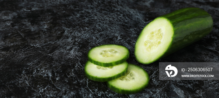 Ripe cucumber and slices on black smoky background