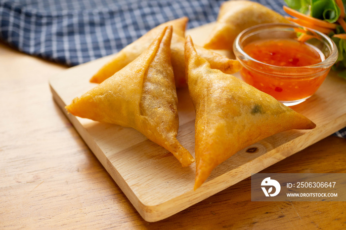 Samosas on wooden board.