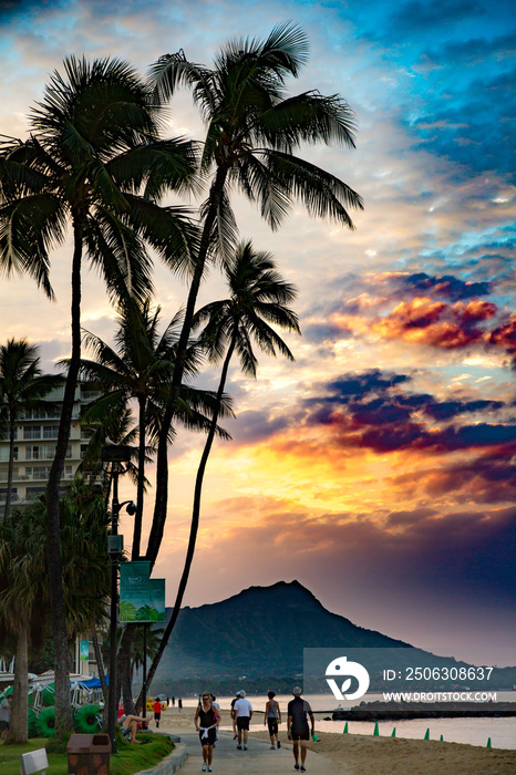 夏威夷威基基——威基基海滩上的日出，背景是棕榈树和钻石头。