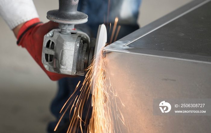 Worker cutting metal part using hand Angle Grinder Machine. Freeze motion spark