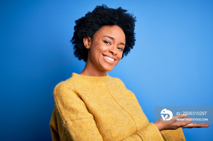 Young beautiful African American afro woman with curly hair wearing yellow casual sweater Inviting t
