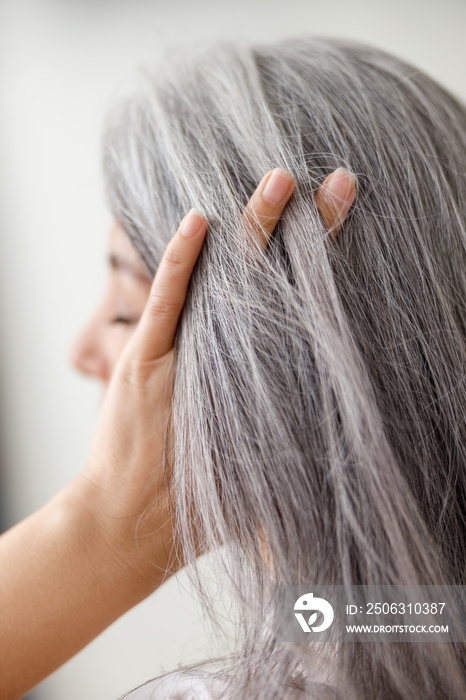 Emotional portraits of a paled long hair asian matured woman on grey background